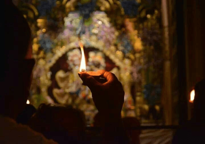 A mangala arati flame held before the altar in the early morning